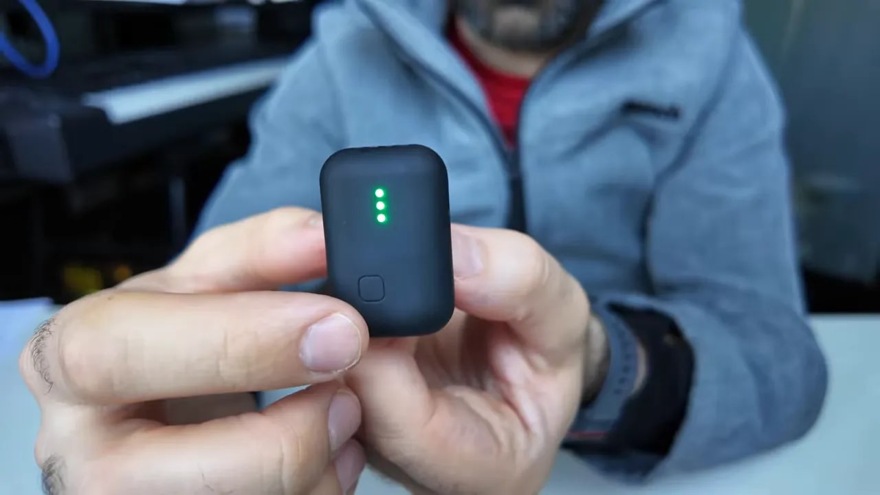 Small recorder held in hand with red status light indicating recording